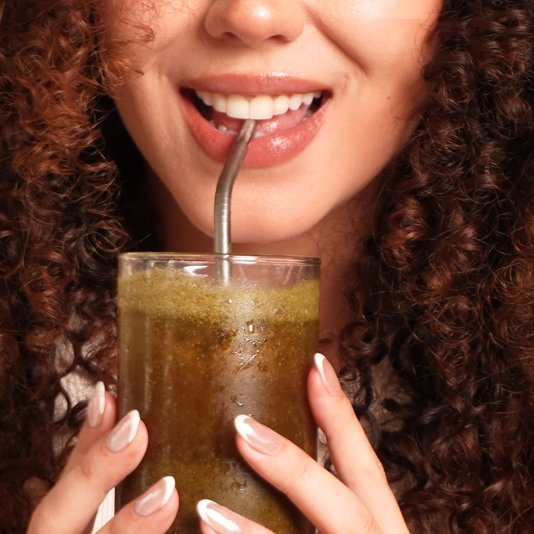 A glass of SOMA Sculpt prepared with water, being consumed through a straw.